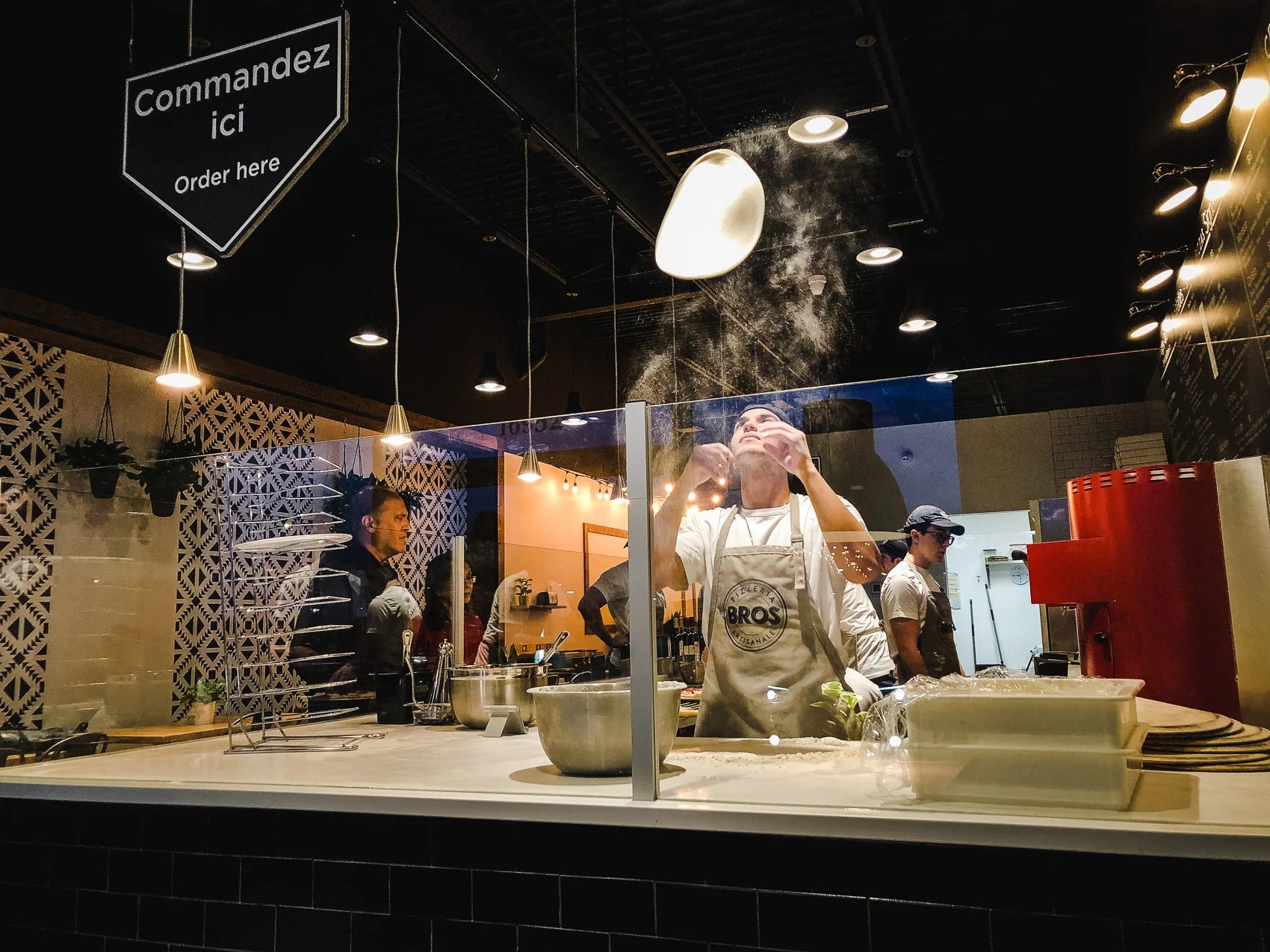Intérieur d'un restaurant Pizzeria Bros, pizzas préparées sur commande au comptoir